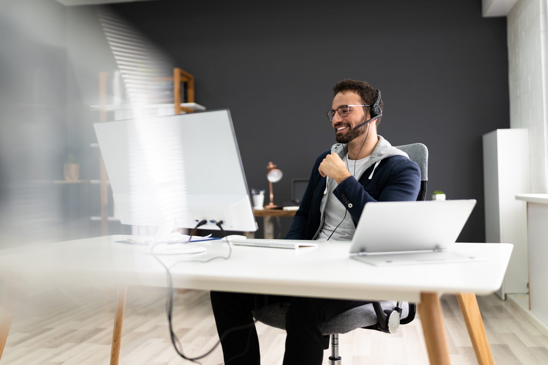Lächelnder Mann, der ein Webinar auf einem großen Bildschirm verfolgt Lächelnder Mann, der ein Webinar auf einem großen Bildschirm verfolgt