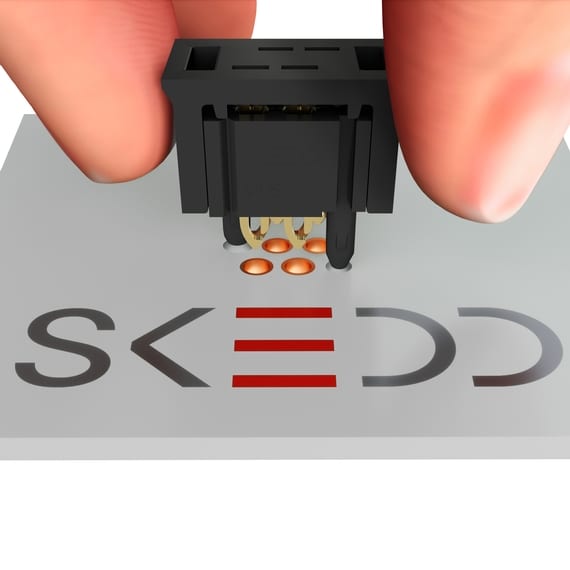 Three fingers holding a SKEED component at the letters
