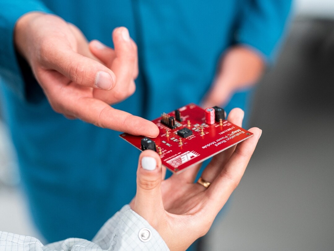 Man pointing on a component on a red circuit board