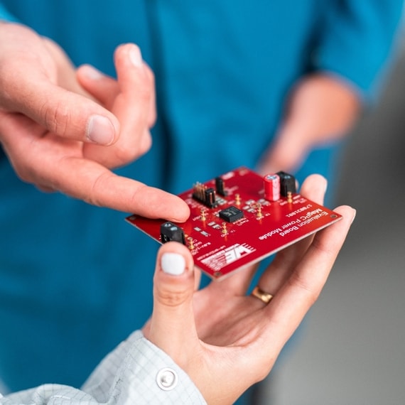 Man pointing on a component on a red circuit board