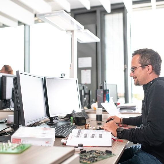 Mann arbeitet an einem Arbeitsplatz mit zwei Bildschirmen