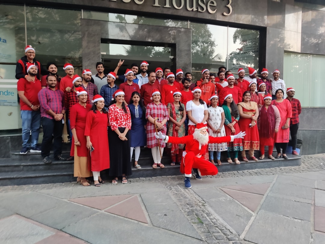 Group of people wearing red standing in front of a building with Santa