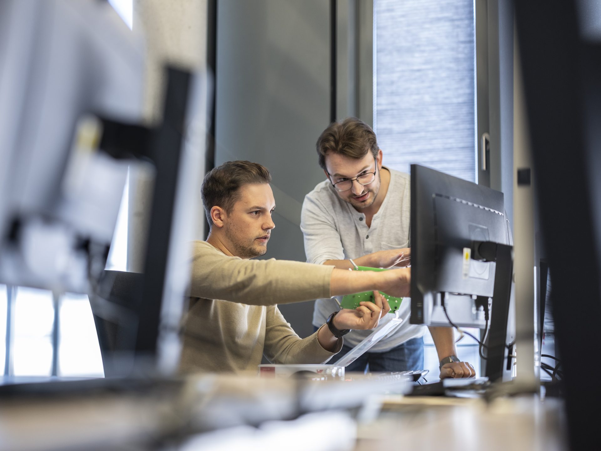 Support Ein Mann erklärt einem anderen Mann am PC etwas