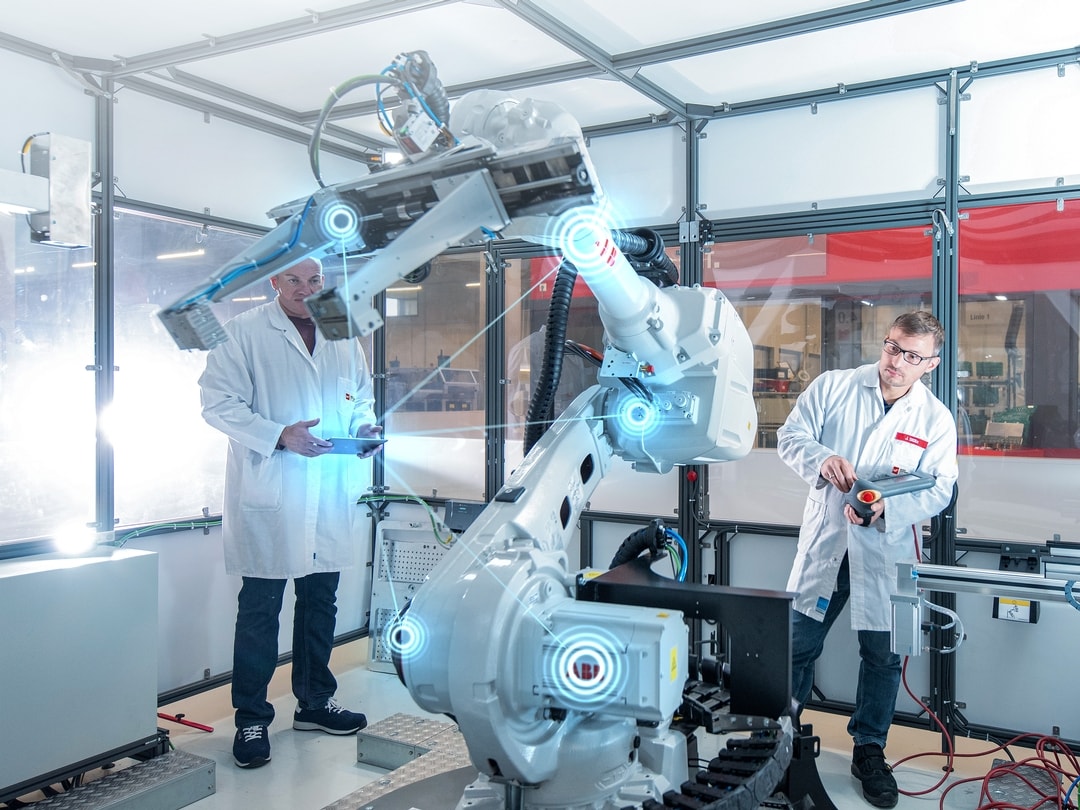 Two people in white coats stand behind a machine and test it