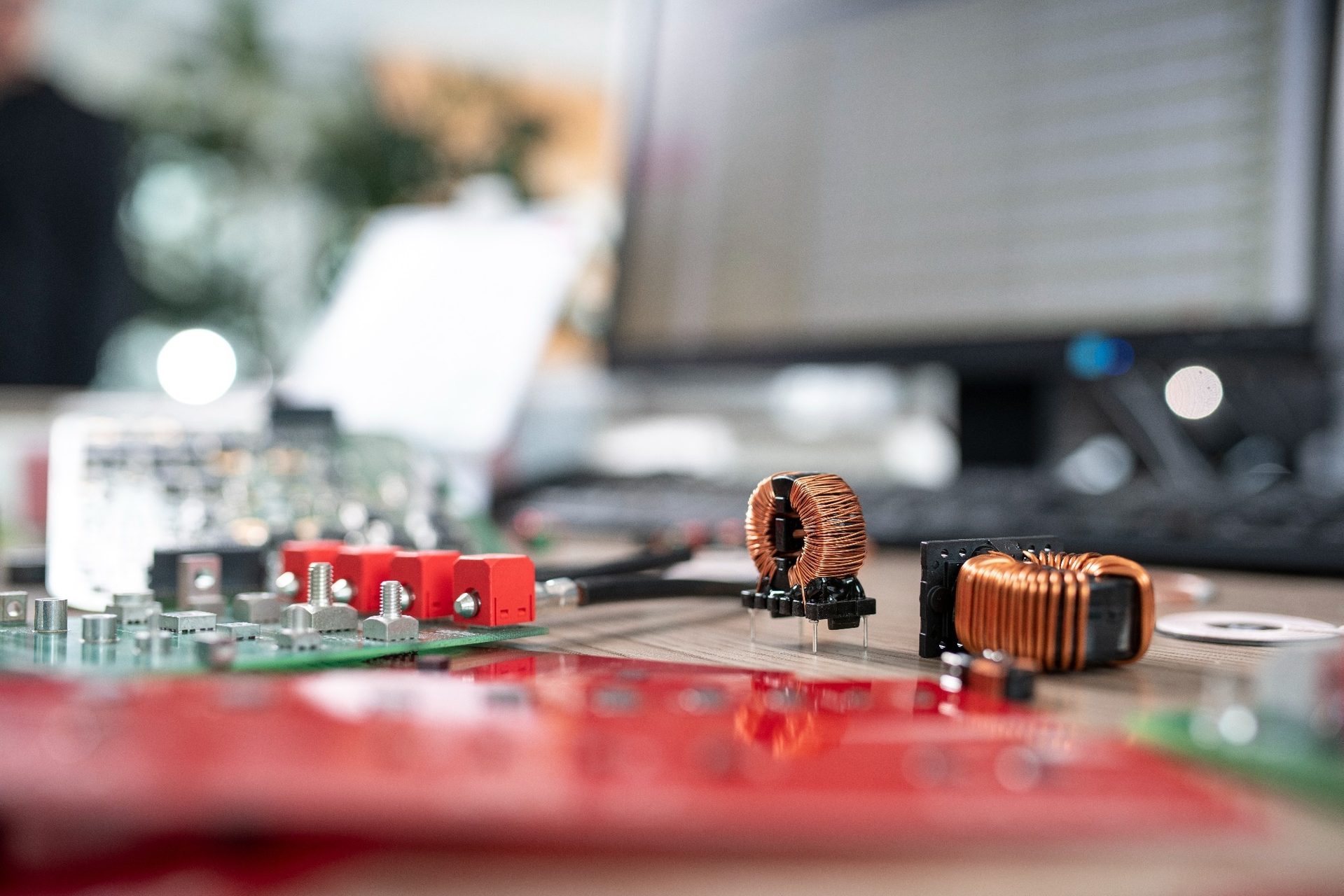 Prototyping at desk Circuit boards and components lie on a table in front of a computer