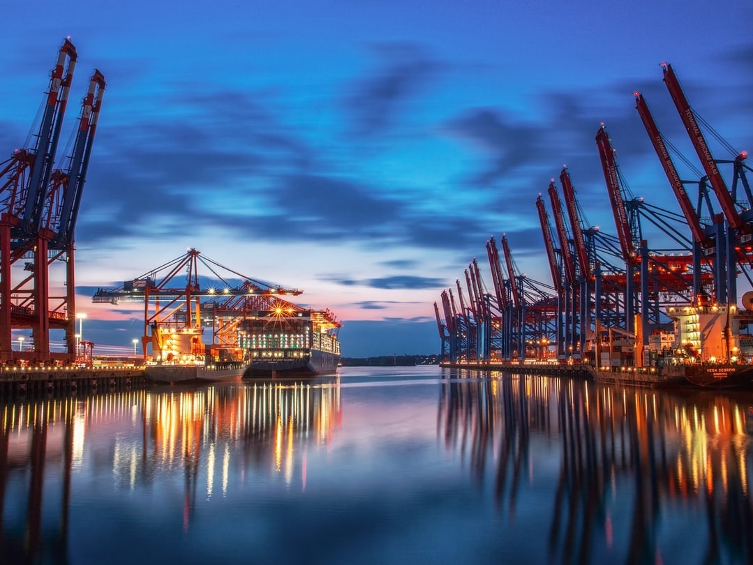 Bild zeigt ein Frachtschiff an einem abendlichen Containerterminal