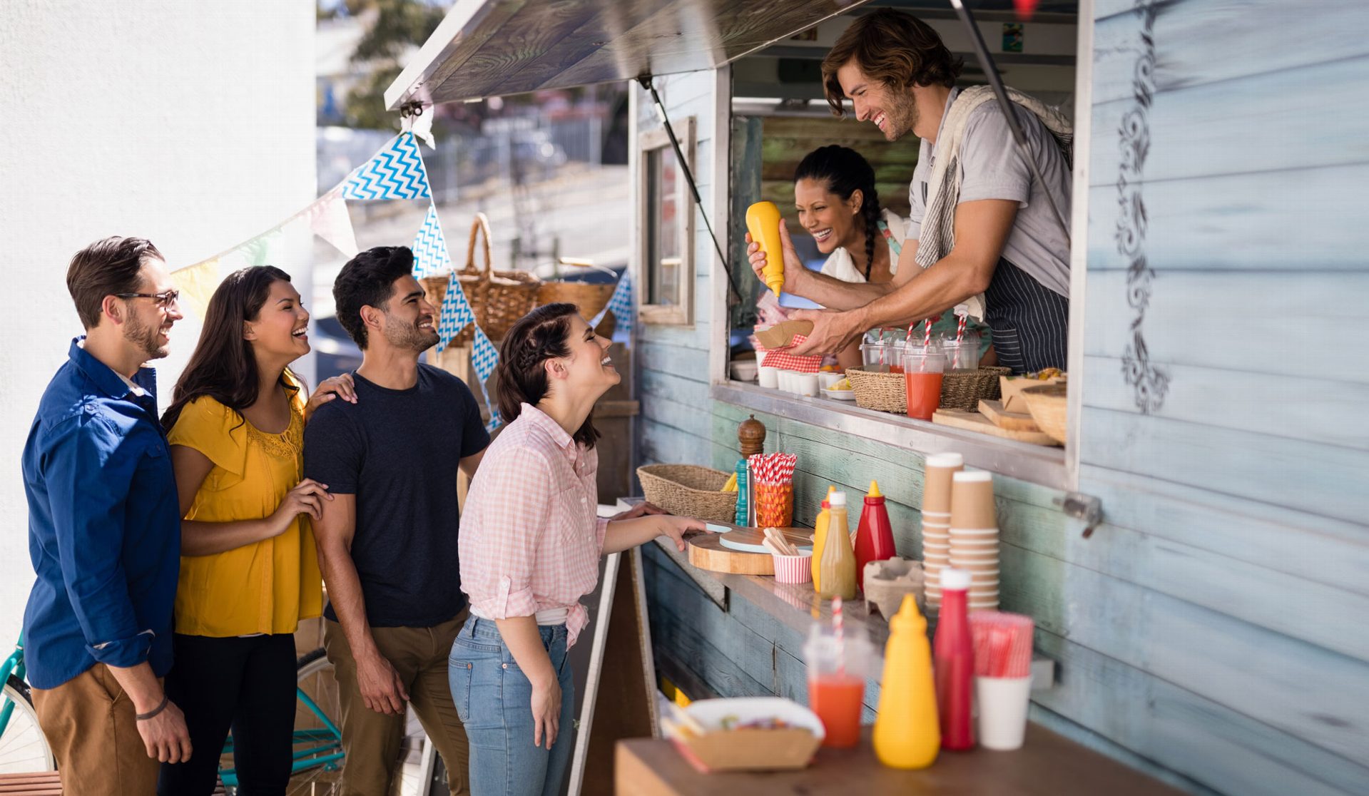 WEBike Eventcatering Junge Leute stehen lachend vor einem Kiosk während sie bedient werden