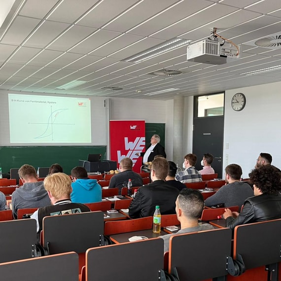 Würth Elektronik präsentiert vor einem Klassenzimmer mit jungen Erwachsenen am Schreibtisch