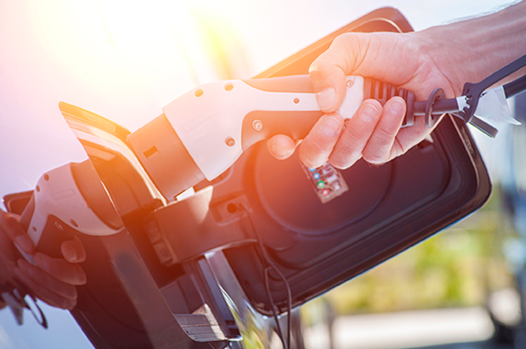 Automotive Applications E-Mobility A person is plugging in the charging cable into the charging port of a car