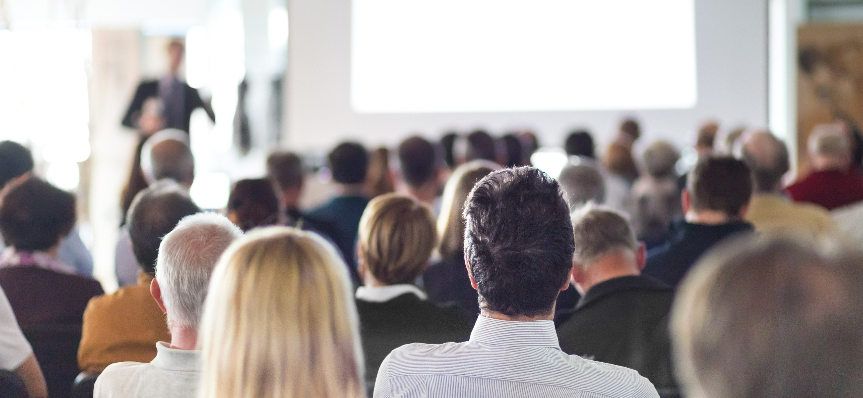 Seminarteilnehmer sitzen vor Sprecher Teilnehmer eines Seminar-Vortrags sitzen in Reihen vor dem Sprecher
