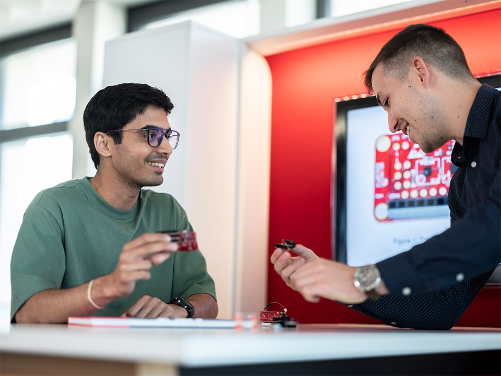 Stipendium Zwei Studenten stehen sich gegenüber und halten ein Produkt in der Hand