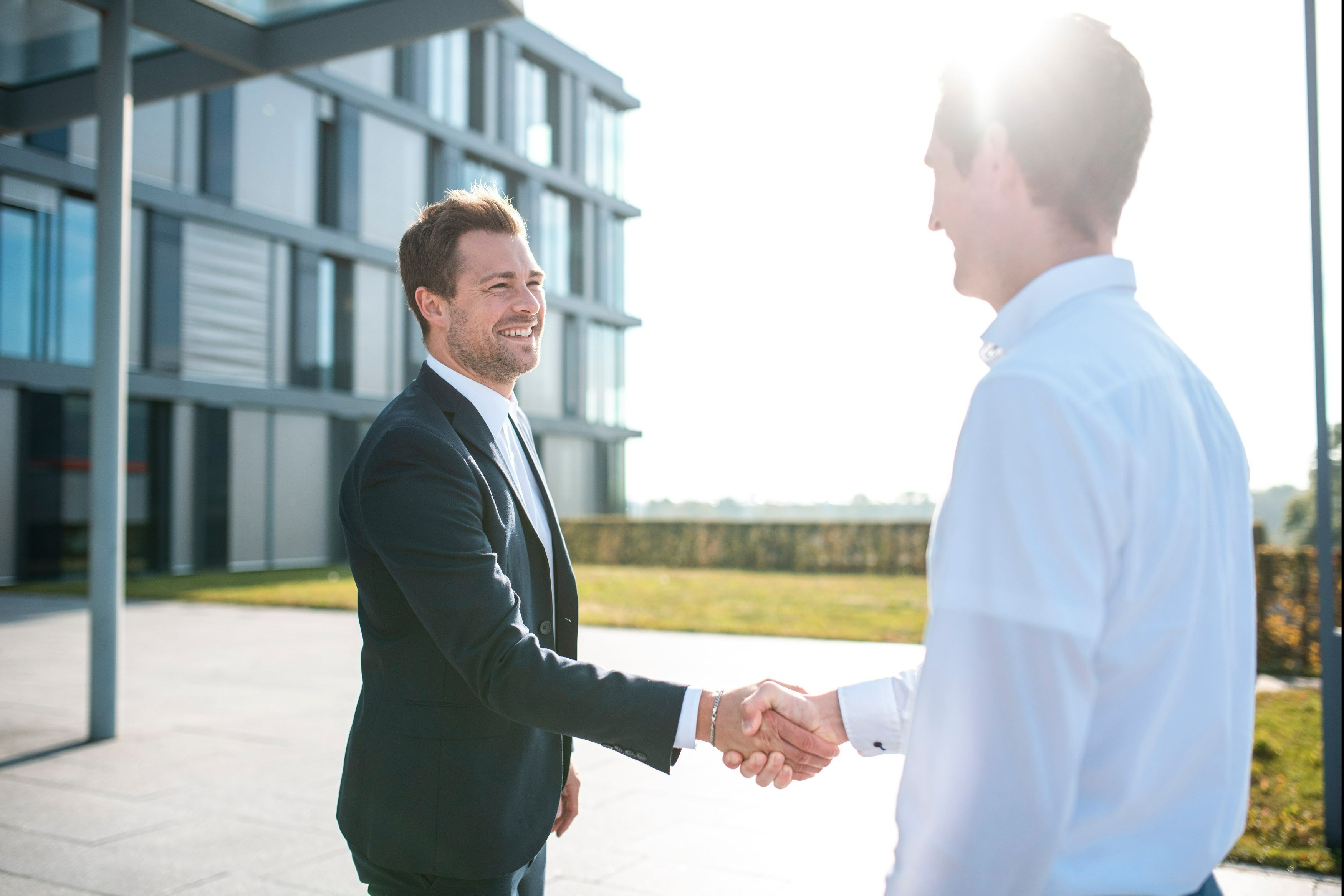Kundenbeziehung 2 Personen vor einem Gebäude schütteln sich die Hände