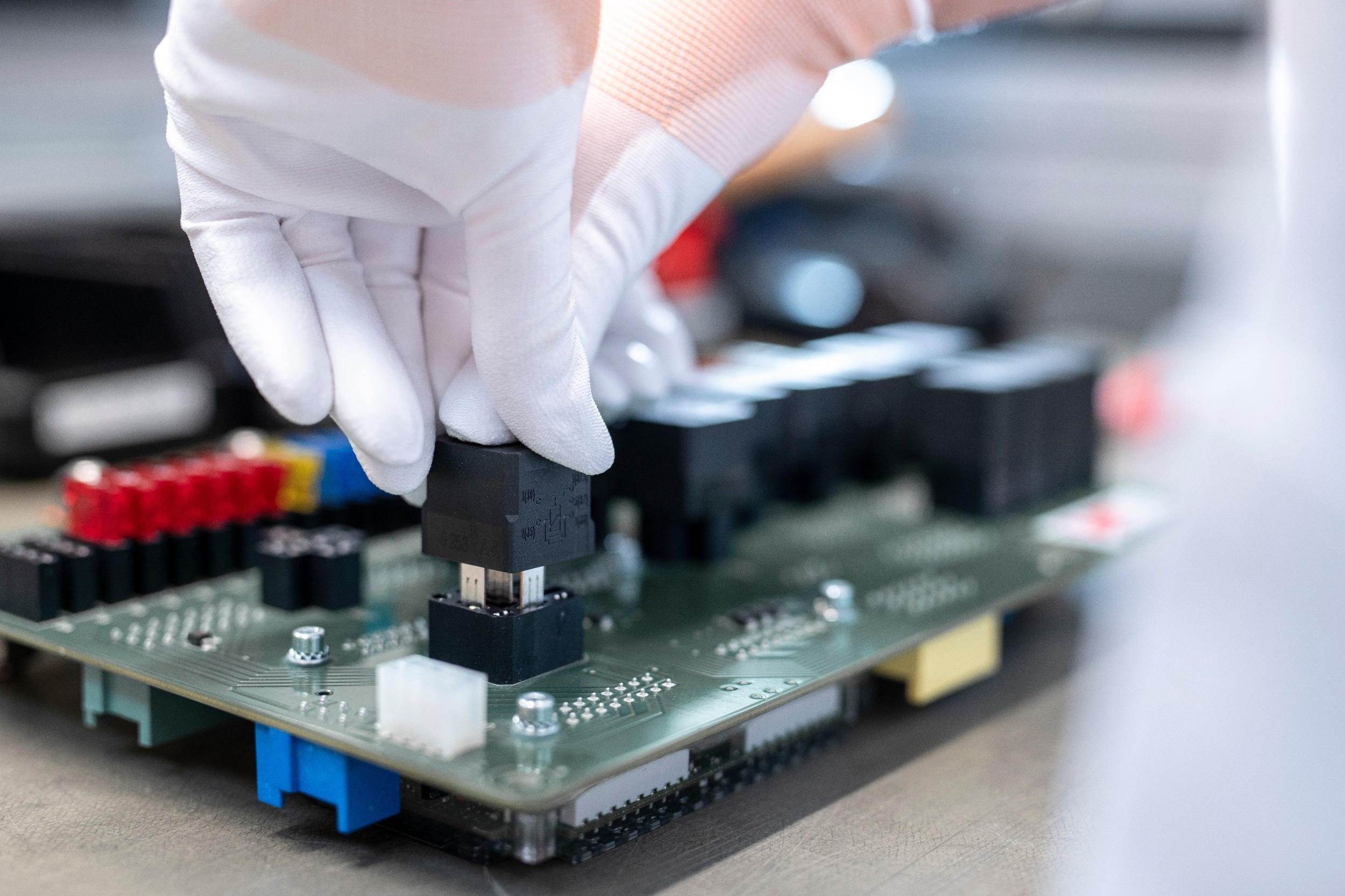 ICCS controller is set on central electrical unit Employee places relay in circuit board by hand