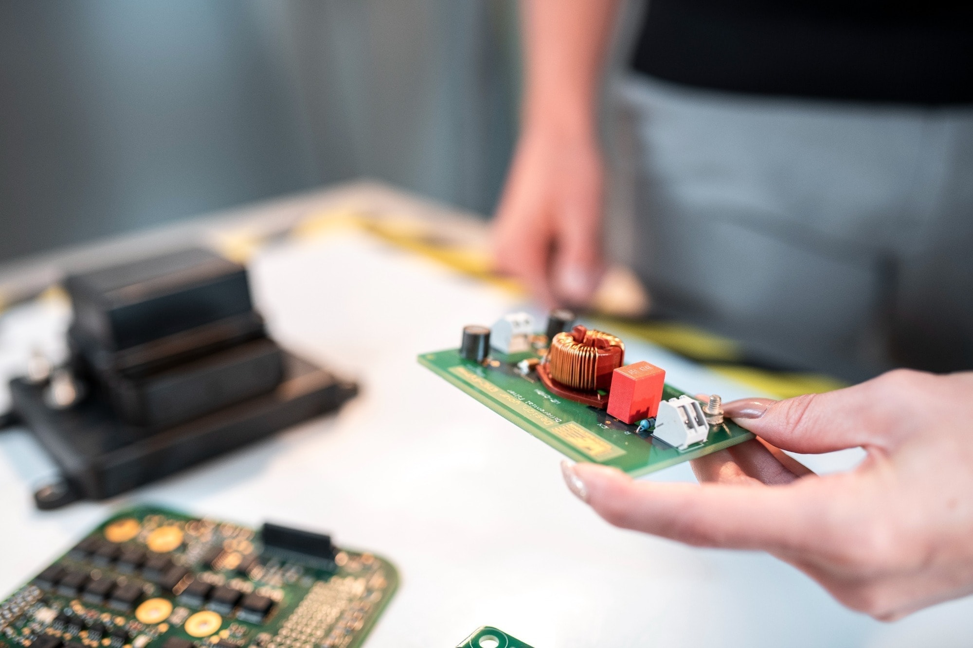 Prototyping einer Platine Leiterplatten mit elektronischen Bauteilen werden mit den Händen auf einem Tisch gehalten