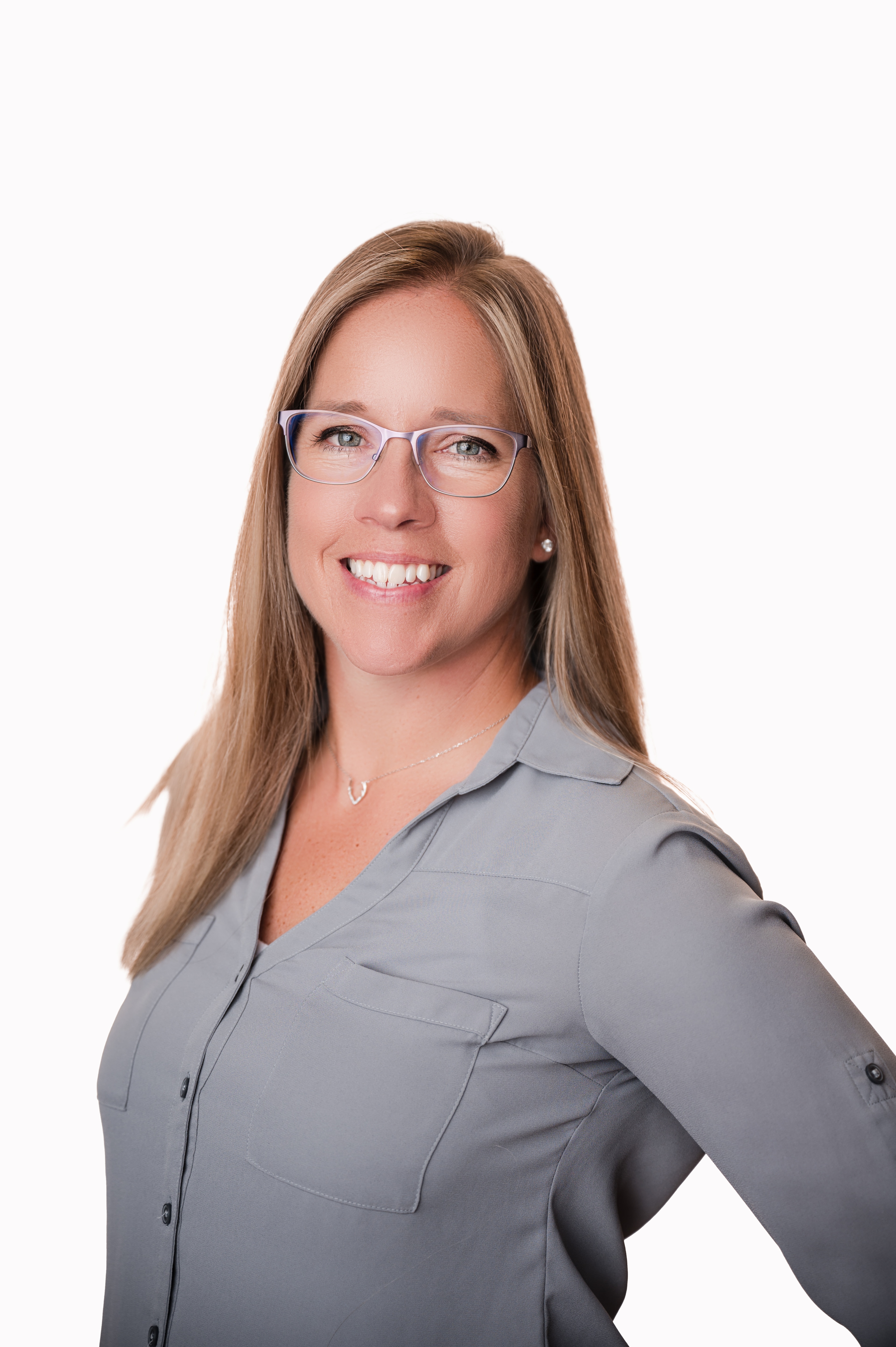 Diversity / Sara Frau steht vor einer weißen Wand und lächelt in die Kamera