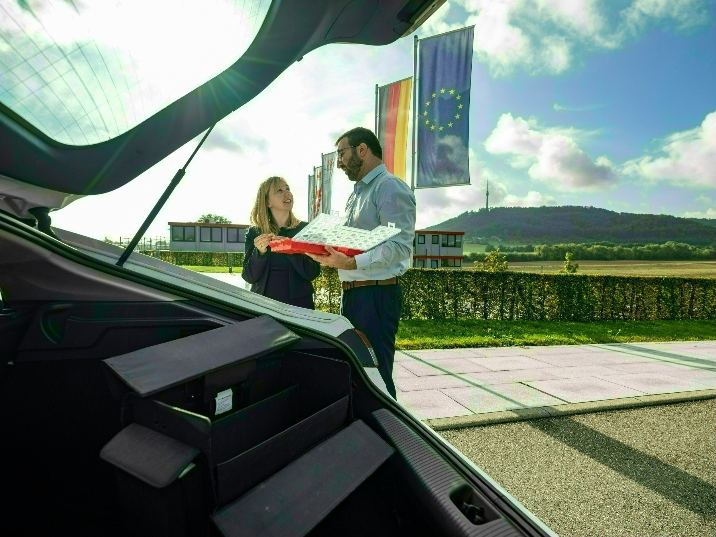 Trainee Technischer Vertrieb Ein offener Kofferraum im Vordergrund und 2 Personen im Verkaufsgespräch im Hintergrund