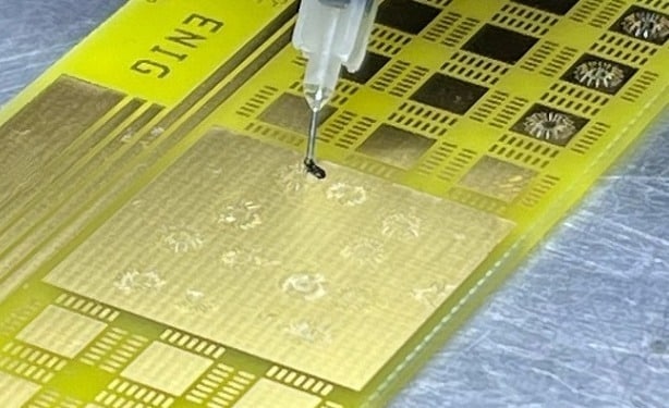 Eine schützende Vergussmasse wird manuell auf die Drahtbond-Verbindungen aufgetragen.