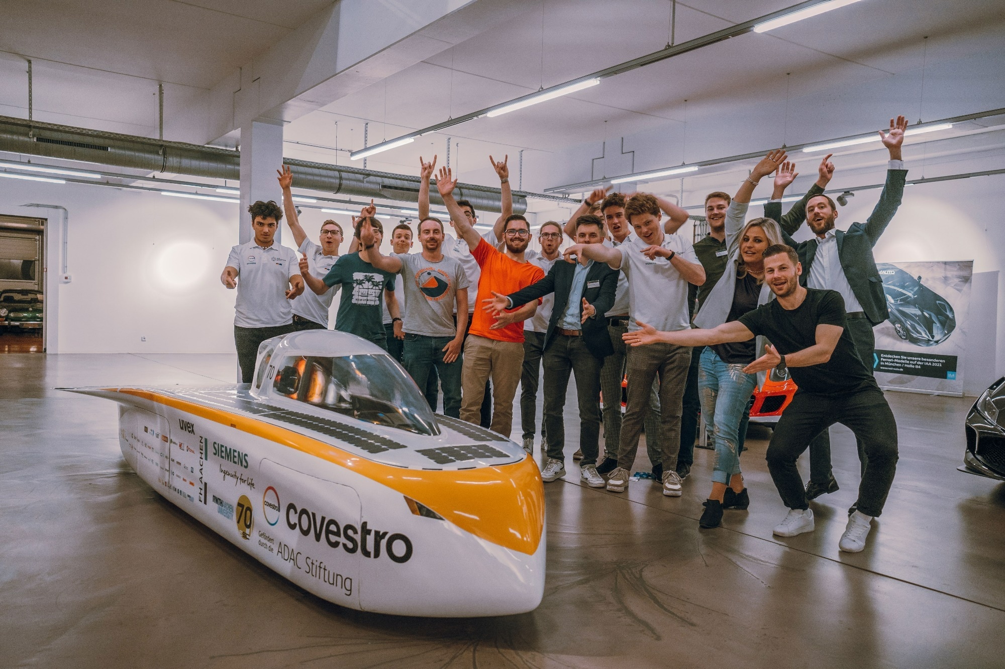 VDE formula students People standing in front of a formula student vehicle holding up their hands