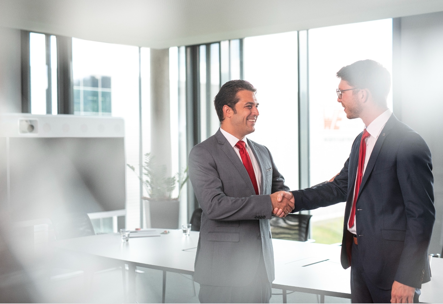 Assessment center or online test? Two people shaking hands and laughing in the meeting room